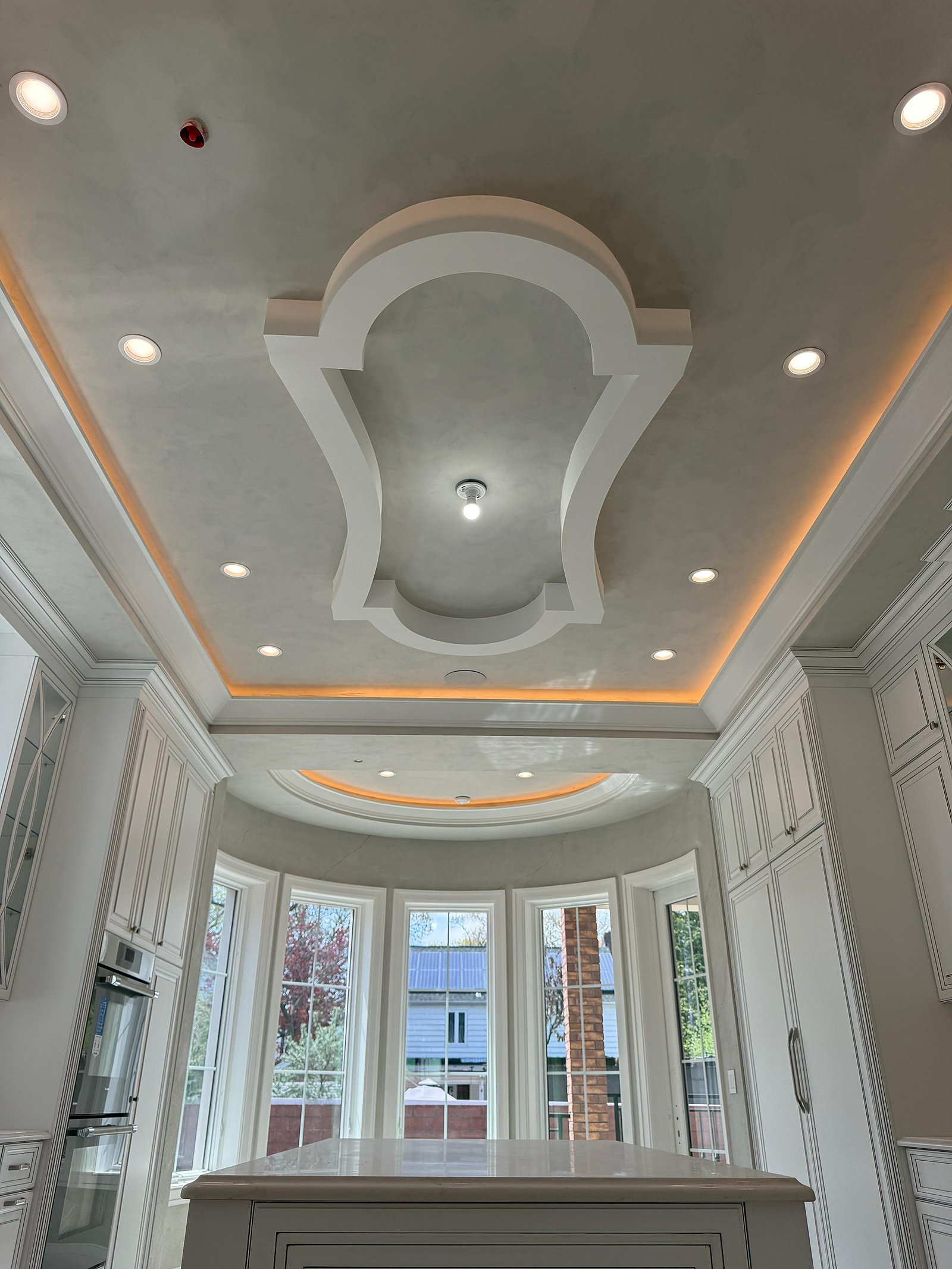 Hand-cast decorative plaster ceiling with a carved central medallion and LED cove over a bay window, Great Neck estate — MarkOn® Walls