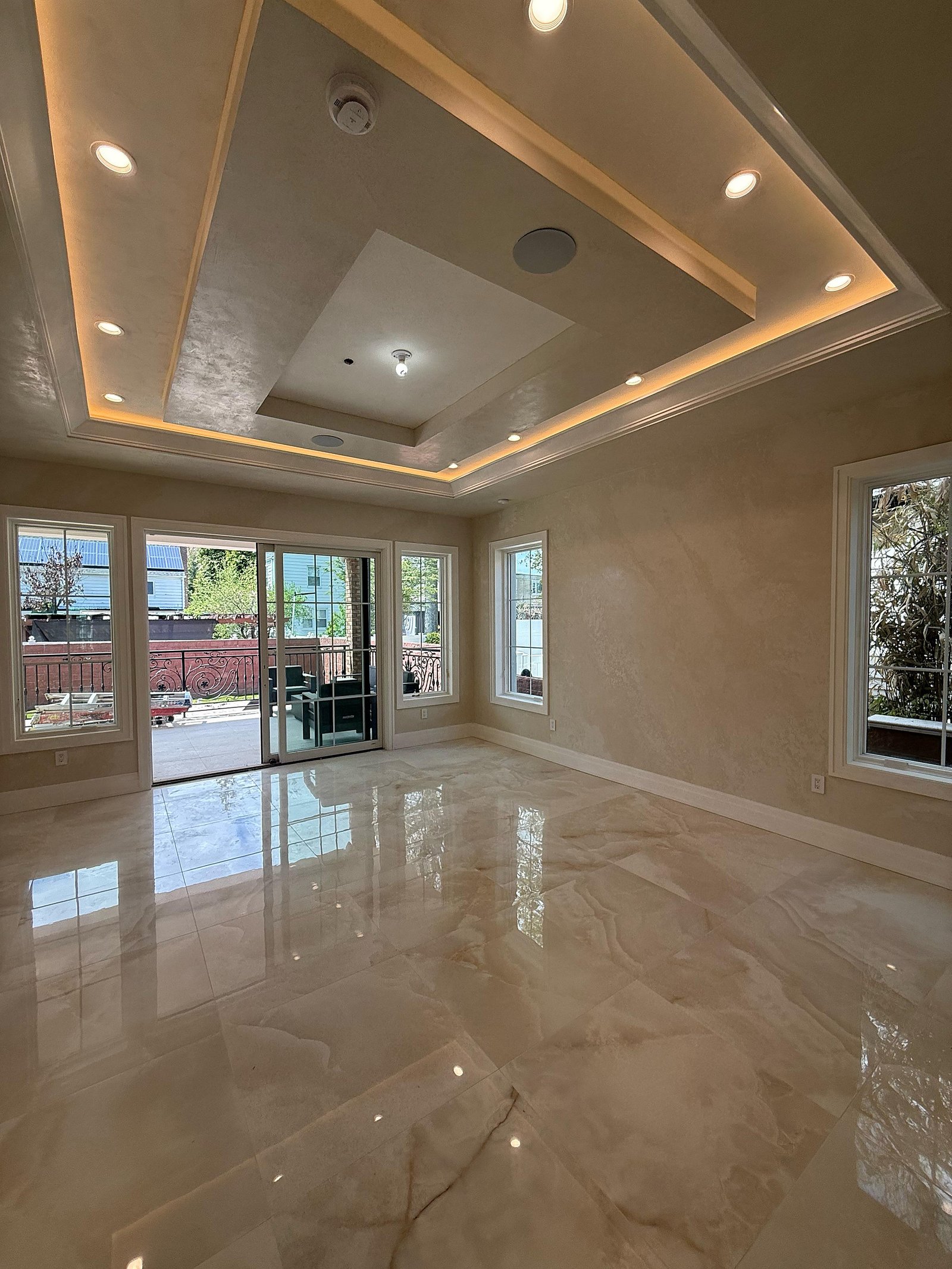 Great Neck estate reception room — burnished polished-plaster walls, LED-cove tray ceiling, polished marble floor, glass doors to a terrace — MarkOn® Walls
