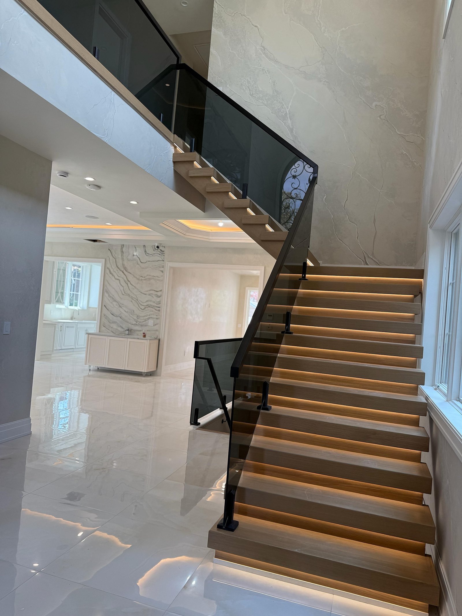 Floating glass-rail staircase against seamless microcement walls in a Great Neck estate — MarkOn® Walls