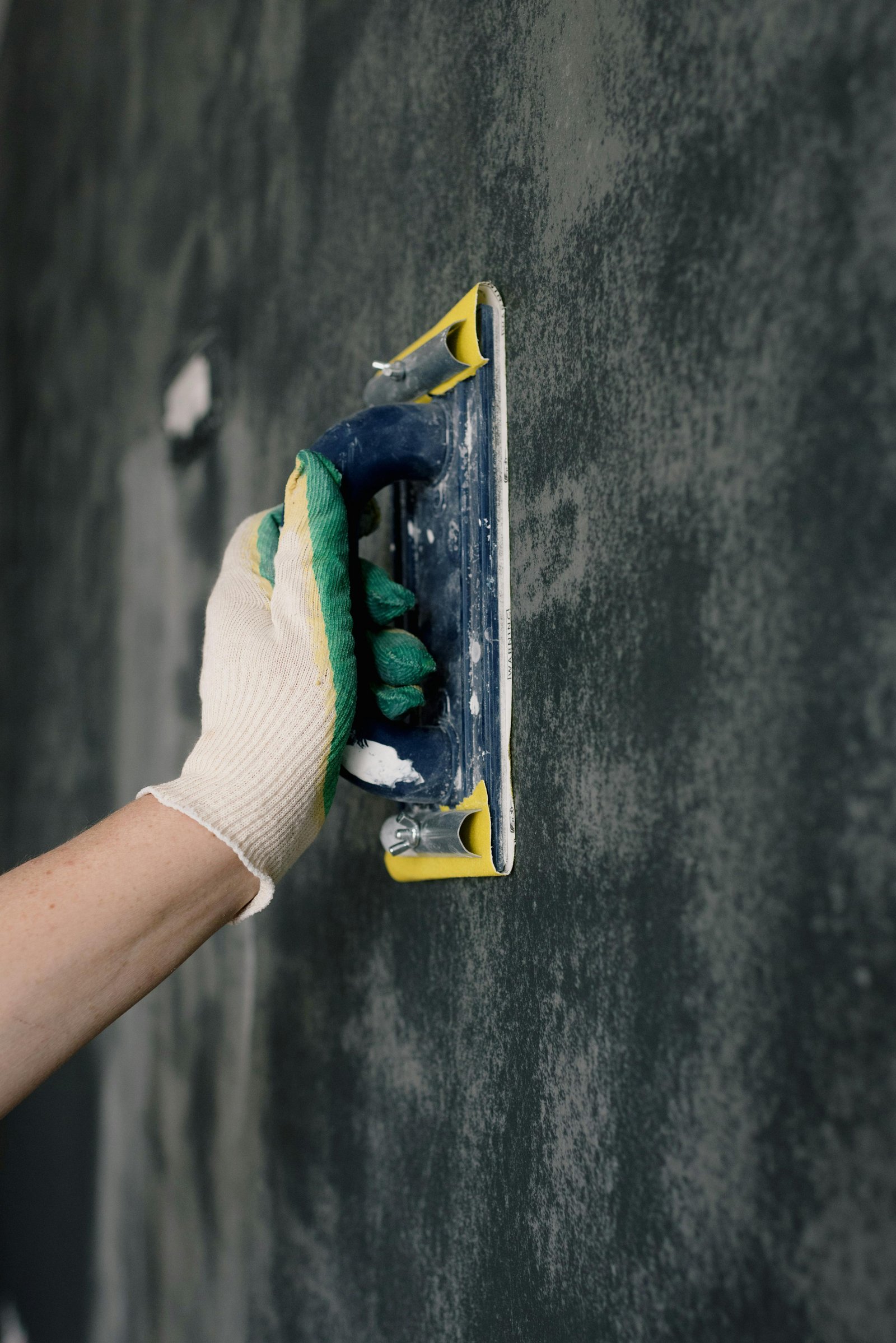 Hand polishing a dark Tadelakt plaster wall with a float — MarkOn® Walls atelier, Fès-trained burnishing