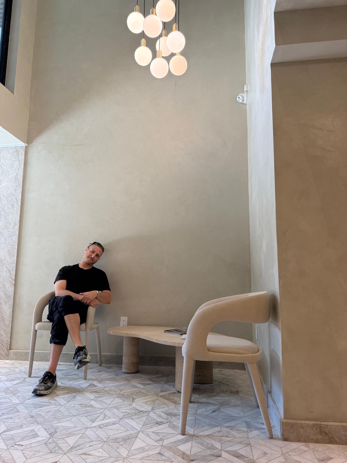 Vlad Markov seated beneath an alabaster pendant cluster in a lime-plaster lobby — MarkOn® Walls