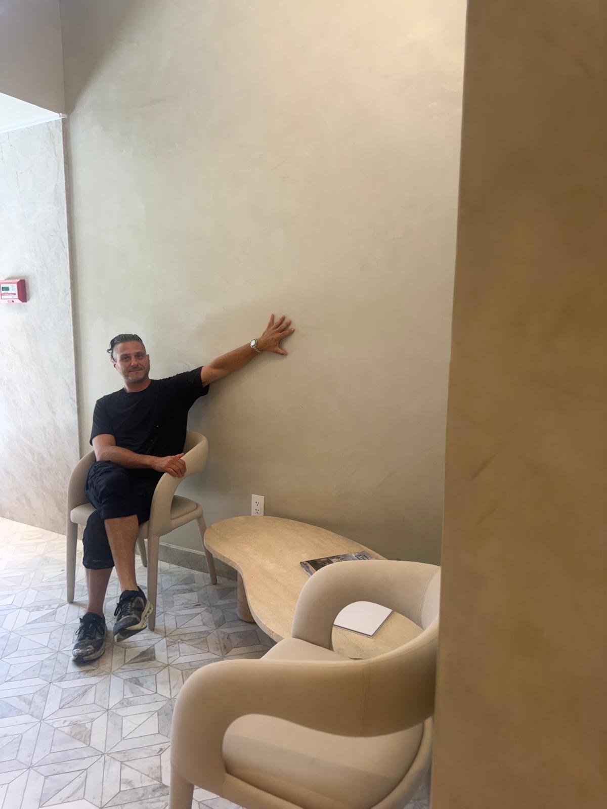 Vlad Markov reading a hand-finished lime plaster wall by hand, on site in a double-height lobby — MarkOn® Walls